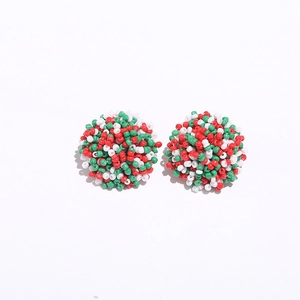 Close-up of handmade beaded stud earrings in red white and green festive patterns