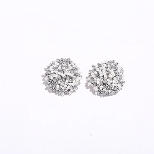 Close-up of bohemian beaded ball earrings featuring white and silver seed beads detail
