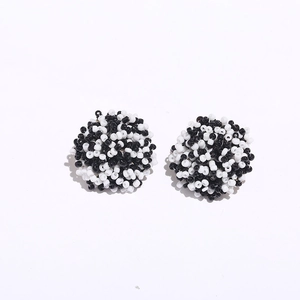 Detail of handmade black and white seed bead cluster earrings with woven texture