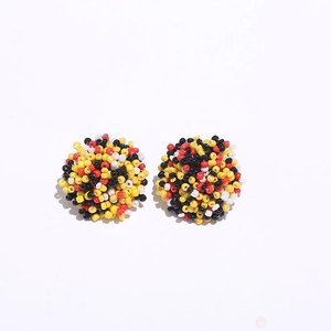 Detail of bohemian handmade beaded stud earrings with red and yellow round spheres
