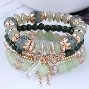 Macro detail of Bohemian multilayered green beaded bracelet with rose gold charms