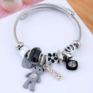 Silver steel bracelet with bear, heart, and black flower charms on a white display