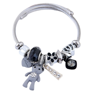 Silver steel cable bracelet with bear charm, faceted beads and heart tag on white background