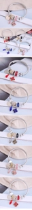 Close-up of four-leaf clover crystal charms and pearl beads on a flexible wire bracelet
