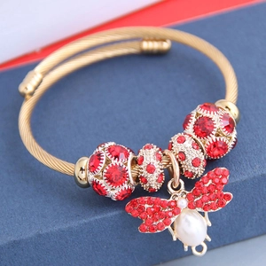 Bracelet jonc bohème en fil d'or avec breloque abeille et perles rouges sur boîte