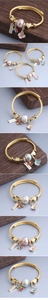 Détail d'un bracelet doré torsadé avec fleurs de cerisier en émail et charm Handmade