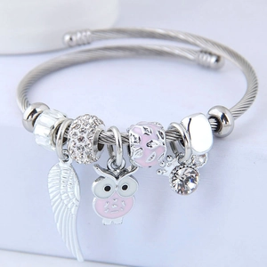 Silver stainless steel spiral bracelet with pink owl and white feather charm detail