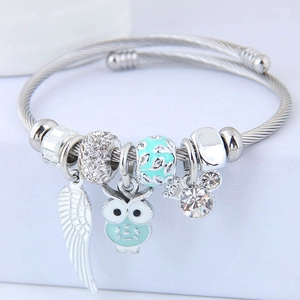 Detailed view of silver wire bracelet with blue owl, feather and crystal charms