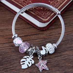 Bracelet DIY avec breloques étoile de mer feuille et cœur rose sur fond vintage