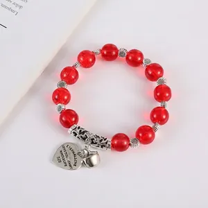 Bohemian red crystal bead bracelet with heart pendant and bell on a white background