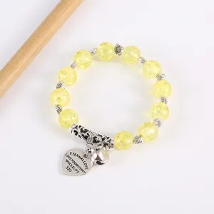 Detail of yellow crackle bead bracelet with silver sunflower charms and heart pendant