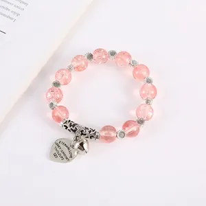 Detail of pink crackle quartz beads bracelet with silver heart charm and bell pendant