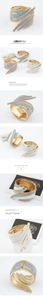 Detail of wide spring-hinged gold metal cuff featuring layered glitter wing textures