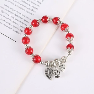 Dettaglio del bracciale di cristallo rosso con ciondoli a foglia, corona e cuore
