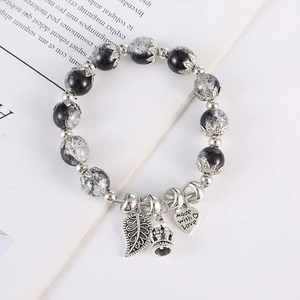 Dettaglio del bracciale con perline, ciondoli a foglia, corona e cuore inciso