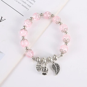 Dettaglio del bracciale in cristallo rosa con ciondoli a cuore, corona e foglia