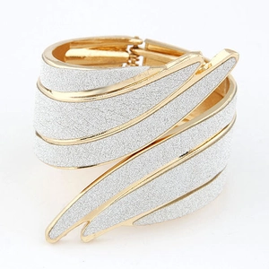 Exaggerated golden metal wing cuff bangle with white glitter frosted texture finish