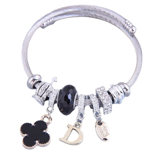 Silver woven wire bracelet with black clover, letter D, and crown charms on white background