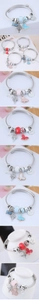 Detail of adjustable stainless steel bangle with fishbone, butterfly and enamel charms