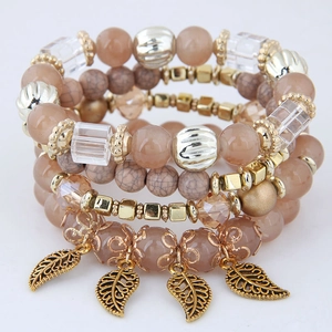Detailed close-up of pink beaded multi-layer bracelet with gold leaf charms and crystal accents