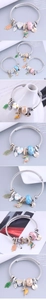 Detailed close-up of wire charm bracelet with hummingbird, heart, and glass bead charms