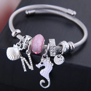 Silver steel wire bracelet featuring pink bead, rhinestone seahorse, and shell charms