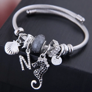 Stainless steel bangle with seahorse and shell charms in a black jewelry box