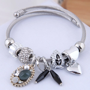 Bohemian style beaded charm bracelet featuring silver cable band and heart shaped pendants