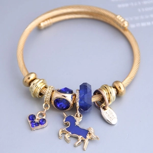 Bracelet torsadé doré orné de perles en cristal bleu et d'un pendentif licorne