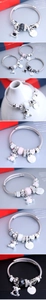 Macro detail of bear charms and heart pendants on twisted stainless steel rope bracelets