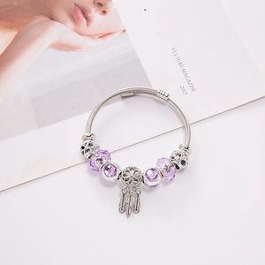 European dreamcatcher charm bracelet with purple crystals and feather pendant on white base