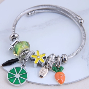 Bracciale in filo d'argento con ciondoli limone, carota e stella su fondo marmo