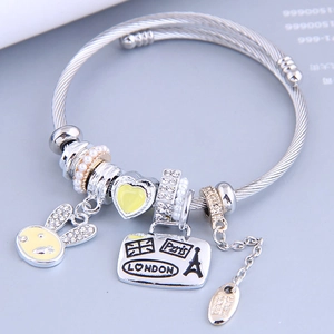 Silbernes Stahldraht-Armband mit gelben Herz- und Hasen-Anhängern und Reise-Themen