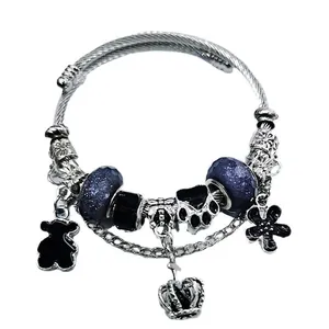 Silver charm bracelet with black bear, crown, and starry blue beads on a cable chain