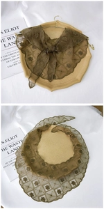Close-up of brown lace triangle scarf with floral embroidery and bow tie detail