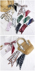 Detailed view of various silk-like printed narrow scarves used as handbag accessories