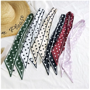 Flat lay of colorful polka dot silk neck scarves in six colors on white fabric