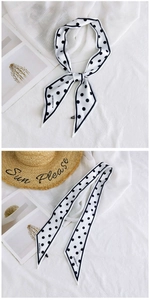Close-up of long white polka dot silk scarf with branded tag and sharp corner ends