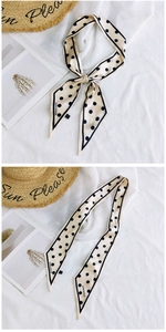 Detailed close-up of a polka dot silk scarf tied in a bow on a sun hat and linen background