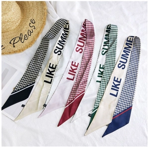 Detailed macro view of houndstooth silk twilly scarves with LIKE SUMMER text on white fabric