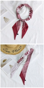 Detail of a red houndstooth narrow scarf with text prints and small care label