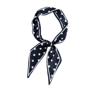 Polka dot skinny neck scarf in black and white satin, tied elegantly on white background