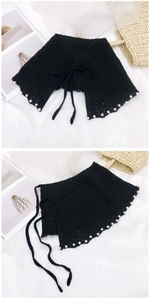 Détail d'un châle au crochet noir avec lacets et perles blanches au style rétro