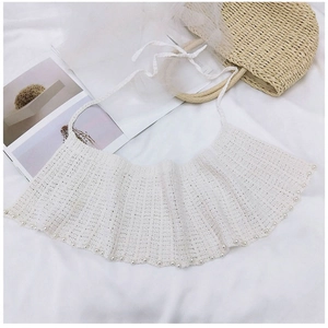 Vue détaillée d'un châle au crochet blanc avec perles décoratives sur fond de tissu doux