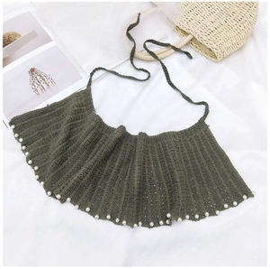 Détail d'un châle au crochet vert foncé avec bordure en perles blanches et texture