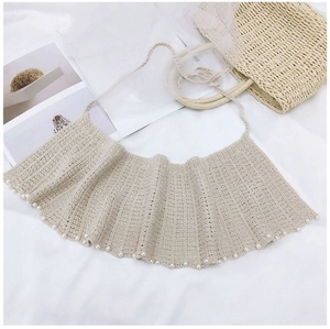 Détail d'un châle en maille crochetée crème avec perles et cordons de serrage fins