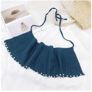 Détail d'un châle tricoté bleu marine avec des perles blanches et des liens à nouer