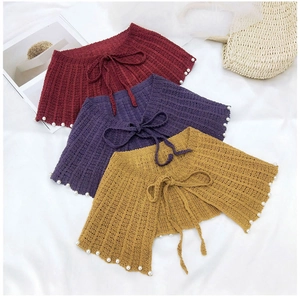 Détail de châles tricotés avec rayures verticales et perles blanches en rouge, violet, jaune