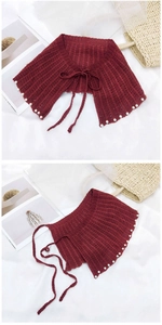 Détail du châle en maille rouge avec perles et fermeture par nœud délicat sur l'épaule