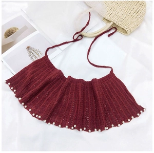 Détails de la maille d'un châle rouge foncé orné de perles blanches décoratives